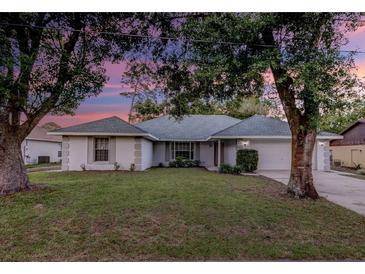 Charming single-story home with mature trees and a well-maintained lawn at dusk at 731 Red Coach Ave, Deltona, FL 32725