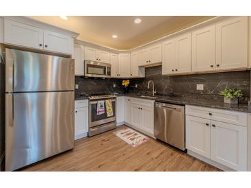 Bright kitchen features stainless steel appliances, white cabinetry, and dark granite countertops at 1235 19Th St, Orlando, FL 32805