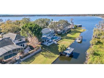 Stunning waterfront home with a private pool, boat dock, and lush landscaping at 6025 Lady Bet Dr, Orlando, FL 32819
