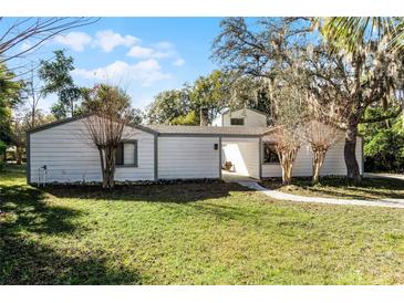Quaint single-story home with lush front lawn and mature landscaping, providing privacy and curb appeal at 203 Red Bud Ln, Longwood, FL 32779