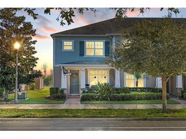 Two-story townhome with light blue exterior, landscaping, and front porch at 15322 Murcott Blossom Blvd, Winter Garden, FL 34787