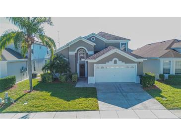 Two-story house with a neutral exterior, two-car garage, and manicured lawn at 8059 King Palm Cir, Kissimmee, FL 34747