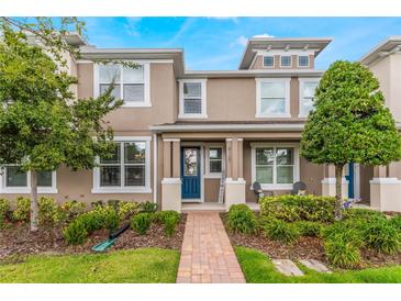 Tan two-story townhome with blue door, brick walkway, and landscaping at 8127 Cadman St, Orlando, FL 32832