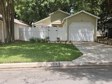 Light green house with white fence, garage, and well-manicured lawn at 513 Harvard Pl, Apopka, FL 32703
