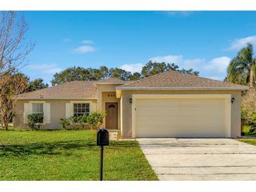 Beige house with a two-car garage and a well-manicured lawn at 849 Jarnac Dr, Kissimmee, FL 34759