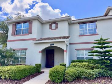Two-story townhome with light-colored siding, brown accents, and landscaping at 1582 Moon Valley Dr, Champions Gate, FL 33896
