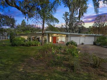 Mid-century modern home with a two-car garage and landscaped lawn at 3644 Lake Shore Dr, Apopka, FL 32703