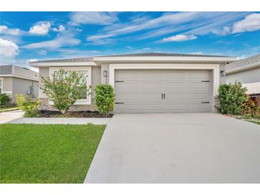 Charming home featuring a two-car garage and well-maintained front lawn under a bright, cloudy sky at 4505 Hummingbird Ln, Haines City, FL 33844