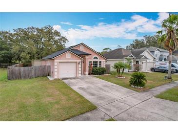 Cute pink house with a two-car garage and well-maintained lawn at 9606 Chandon Dr, Orlando, FL 32825