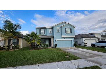 Two-story light blue house with a two-car garage and landscaped lawn at 1706 Chatsworth Cir, Saint Cloud, FL 34771
