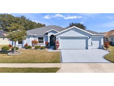 Charming single-story home featuring a well-manicured lawn, a two-car garage, and beautiful landscaping at 26812 Augusta Springs Cir, Leesburg, FL 34748