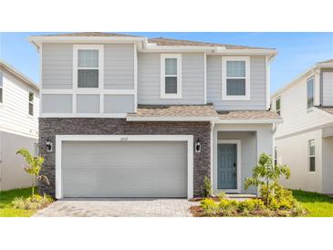 Two-story house with gray siding, stone accents, and a two-car garage at 3937 Lana Ave, Davenport, FL 33897