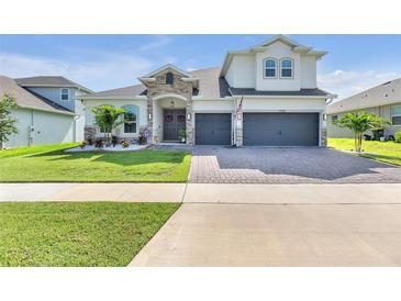 Two-story house with stone accents, two-car garage, and landscaped yard at 4438 Renly Ln, Clermont, FL 34711