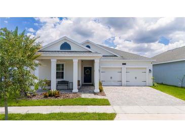 White house with two-car garage, covered porch, and landscaping at 4533 Sequel Rd, Kissimmee, FL 34746