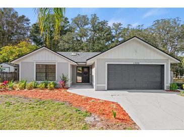Updated home exterior boasts a gray and white color scheme, landscaping, and a two-car garage at 1395 Kenneth Ave, Casselberry, FL 32707