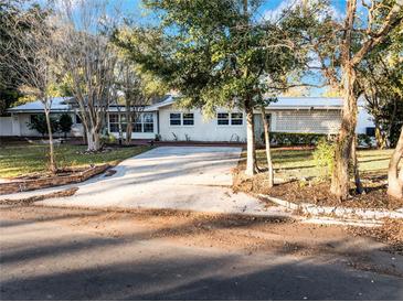 White mid-century modern home with large windows, mature trees, and a long driveway at 1642 Athens St, Lakeland, FL 33803