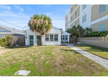 Cozy home exterior with a well-maintained lawn, mature palm trees, and a stone pathway to the entryway at 718 N Grandview Ave, Daytona Beach, FL 32118