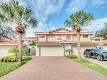 Two-story condo with tile driveway, attached garage, and lush landscaping at 7760 Windbreak Rd, Orlando, FL 32819