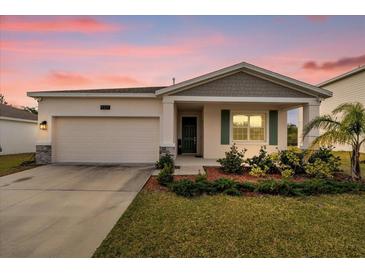 One-story home with gray siding, green door, and landscaped yard at 9331 Revere Ave, Leesburg, FL 34788