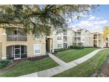 Exterior of the apartment building showcasing landscaping and a walkway at 2303 Butterfly Palm Way # 201, Kissimmee, FL 34747