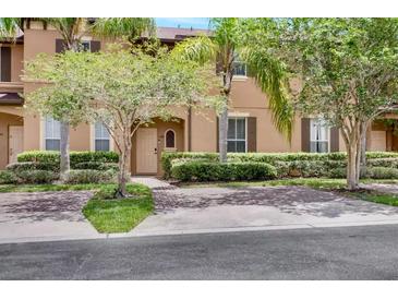 Tan two-story townhome with a landscaped front yard and brick paver driveway at 120 Palermo St, Davenport, FL 33897