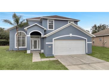 Two-story house with gray exterior, white garage door, and green lawn at 2556 Volta Cir, Kissimmee, FL 34746