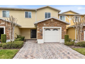 Inviting two-story townhome boasts a charming exterior, featuring stone accents and a paved driveway at 10125 Shadow Leaf Ct, Orlando, FL 32825