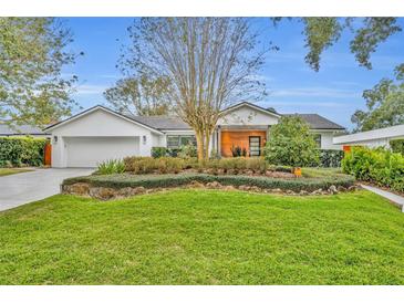 Mid-century modern home with landscaped yard and attached two-car garage at 1816 Bimini Dr, Orlando, FL 32806