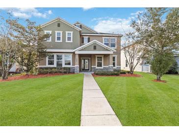 Two-story house with green siding, stone accents, and a manicured lawn at 1942 J Lawson Blvd, Orlando, FL 32824