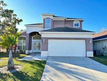 Two-story house with a two-car garage and landscaped lawn at 12061 Greco Dr, Orlando, FL 32824