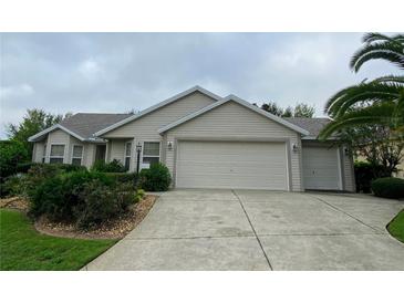 Tan house with double garage and manicured landscaping at 2530 Saffron Ln, The Villages, FL 32162