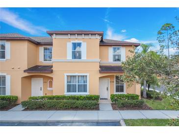 Two-story townhome with light peach exterior, landscaping, and a sidewalk at 2740 Coupe St, Kissimmee, FL 34746