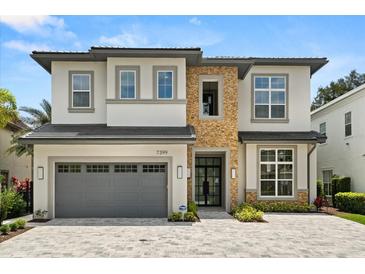 Stunning two-story home featuring a stone facade, manicured landscaping, and a spacious two-car garage at 7399 Gathering Ct, Reunion, FL 34747