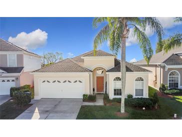 Attractive single-story house with a two-car garage, landscaping, and palm tree at 8030 King Palm Cir, Kissimmee, FL 34747