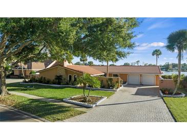 Single-story home with a two-car garage, mature landscaping, and paver driveway at 145 Spring Lake Hills Dr, Altamonte Springs, FL 32714