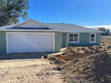 Newly constructed light green house with a white garage door at 25 Locust Loop Ln, Ocala, FL 34472