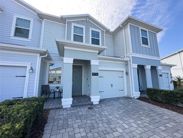 Two-story townhome with gray siding, paver driveway, and landscaping at 4736 Tribute Trl, Kissimmee, FL 34746