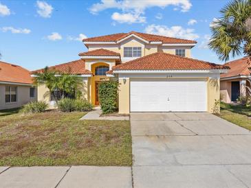 Two-story house with a tan exterior, tile roof, and a two-car garage at 204 Paloma Dr, Davenport, FL 33837