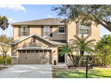 Two-story house with tan siding, brown accents, and a two-car garage at 20811 Sullivan Ranch Blvd, Mount Dora, FL 32757