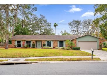 Brick ranch home with a landscaped lawn and attached garage at 223 Royal Oaks Cir, Longwood, FL 32779