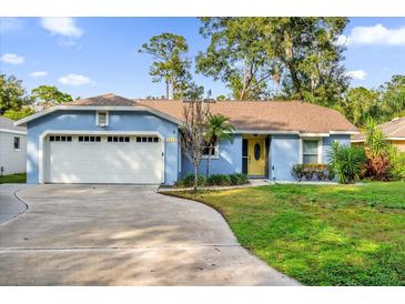 Cute blue house with white garage door and yellow front door, nicely landscaped lawn at 1255 S Timberland Trl, Altamonte Springs, FL 32714