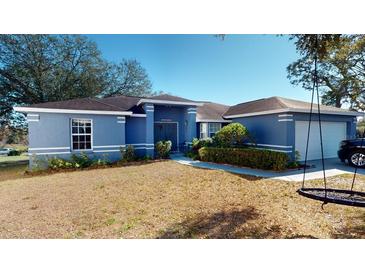 Blue house with a two-car garage and a well-maintained lawn at 3917 Derby Dr, Lakeland, FL 33809