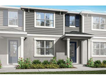 Two-story townhome with gray siding, blue door, and landscaping at 9847 Walkway Dr, Orlando, FL 32832