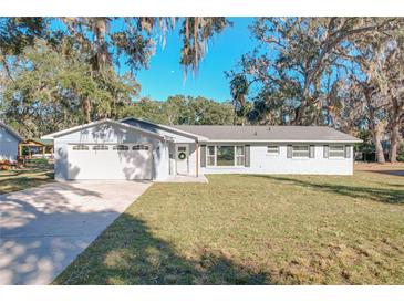 Newly renovated home with gray exterior, white garage door, and landscaped lawn at 30722 Cove Rd, Tavares, FL 32778