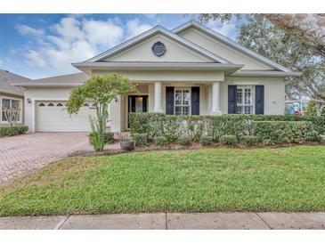 Beautiful one-story home with a landscaped lawn, brick driveway, and a charming front porch at 13607 Zori Ln, Windermere, FL 34786