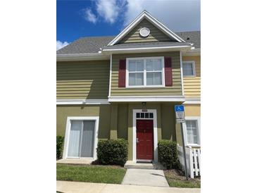 Inviting exterior of townhome with red door and landscaping at 2600 Lodi Cir # 101, Kissimmee, FL 34746