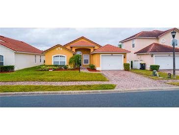 Bright yellow house with a two-car garage and well-manicured lawn at 308 Robin Rd, Davenport, FL 33896