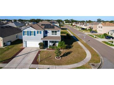 Aerial view of a charming two-story home with solar panels, a well-maintained lawn, and a quiet neighborhood at 6163 Forest Ridge Way, Winter Haven, FL 33881