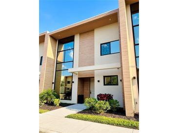 Modern two-story townhouse showcasing a stylish facade, a landscaped front yard, and large windows at 7535 Brooklyn Dr, Kissimmee, FL 34747