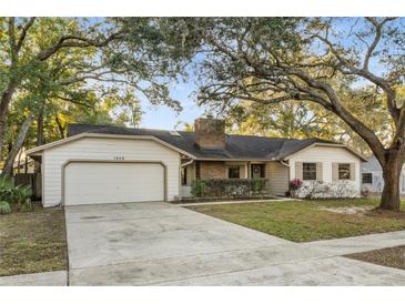 Single story home with attached garage, landscaping, and a large driveway at 1404 N Cove Blvd, Longwood, FL 32750